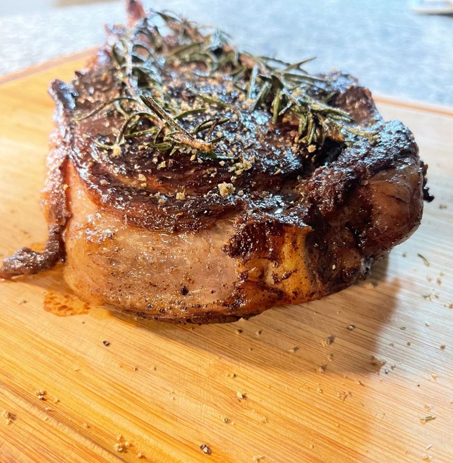 Rosemary-crusted ribeye resting on a cutting board